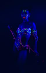Artistic neon fashion portrait under blue UV light, showcasing bold makeup and colorful bikini.